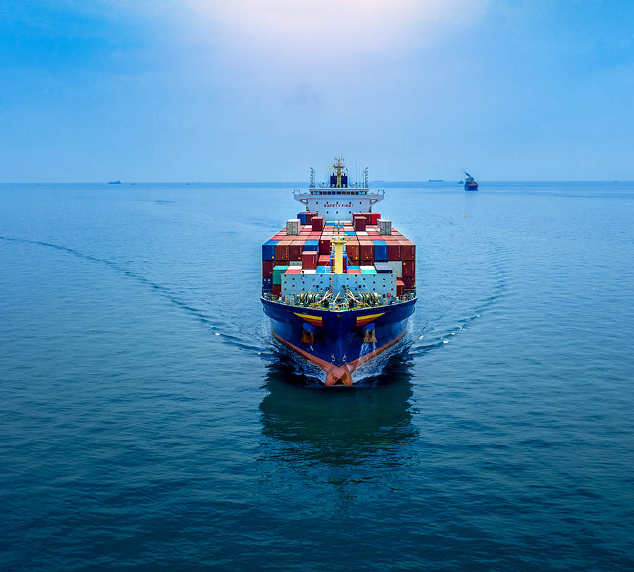 Aerial in front view of cargo ship carrying container and runnin